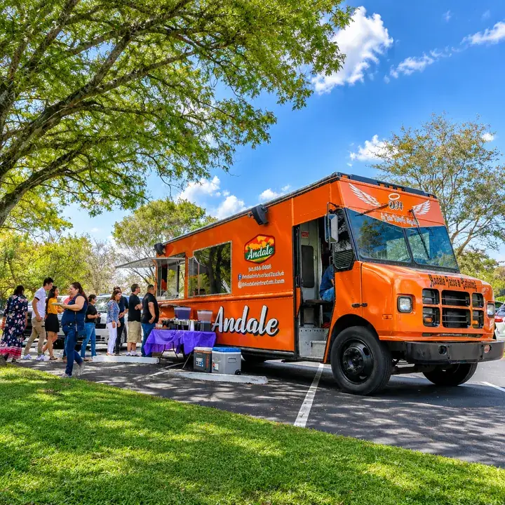 Customers lining up at an orange food truck